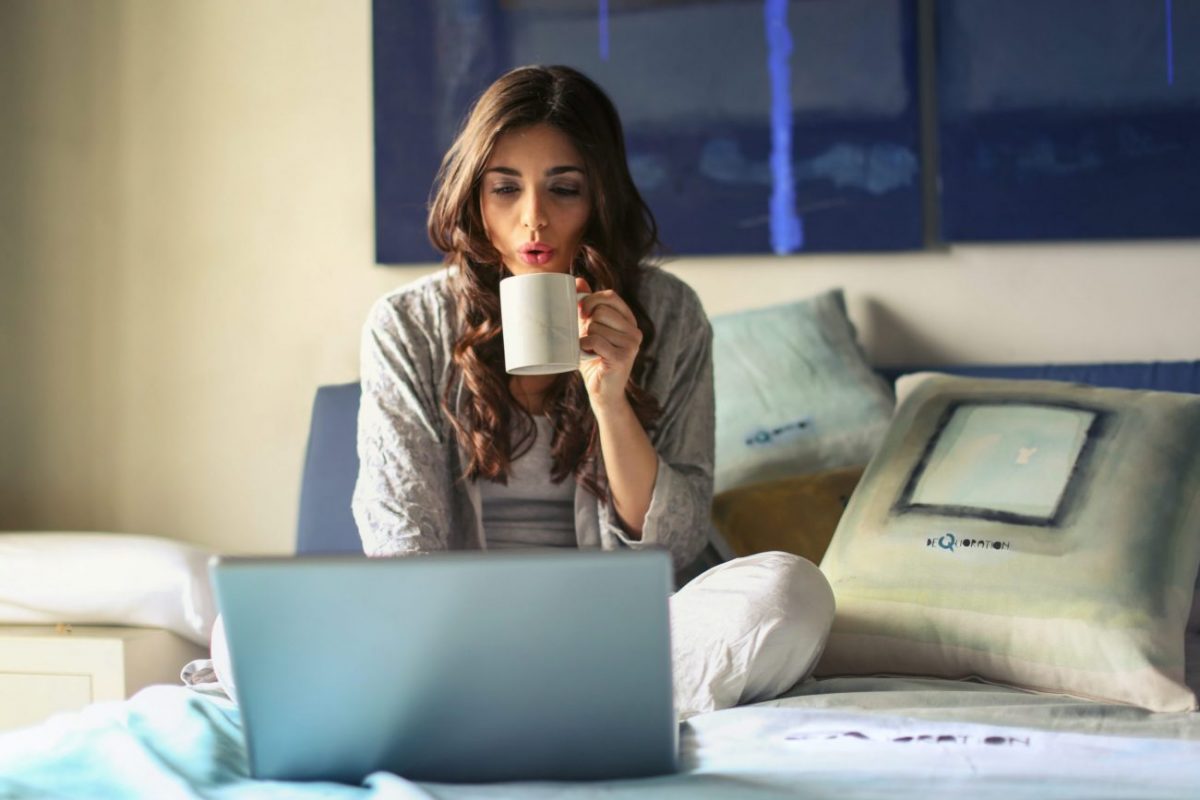 woman drinking tea at laptop having online therapy with Neil Cox Hypnotherapy