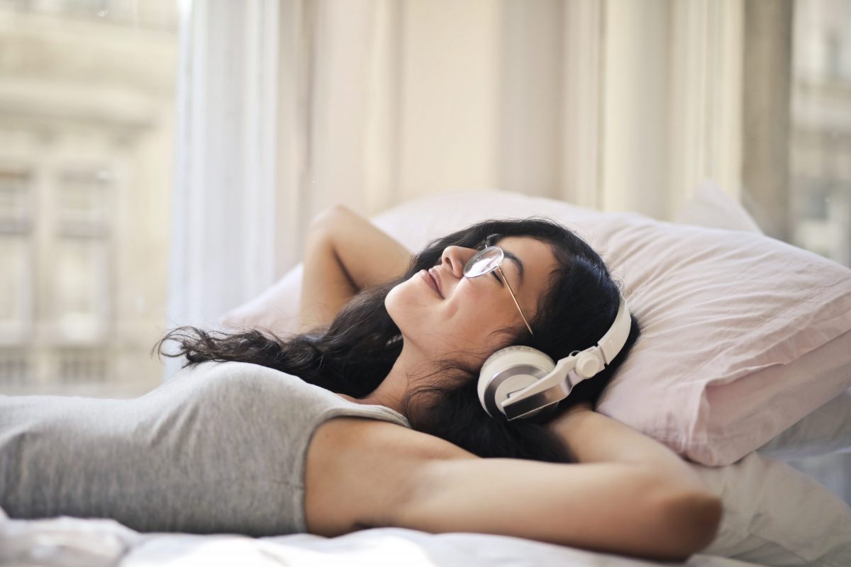 woman lying down with headphones having online therapy with Neil Cox Hypnotherapy